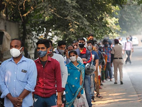 File photo: people queue up to get tested for COVID-19 as a thick quilt of smog lingers over New Delhi, India.