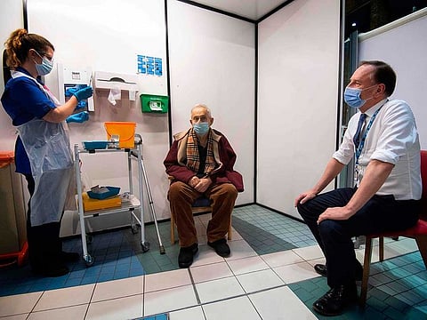 Simon Stevens (R), Chief Executive of the NHS, watches as a nurse administers a dose of the Pfizer-BioNTech Covid-19 vaccine to Frank Naderer (C), 82, at Guy's Hospital in London on December 8, 2020 as the UK starts its biggest ever vaccination programme.