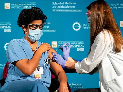 Dr. Sheetal Sheth (L) an OB-GYN and Medical Director for Labour and Delivery at George Washington University Hospital, is vaccinated for COVID-19 by nurse Lillian Wirpsza, December 14, 2020, in Washington, DC.