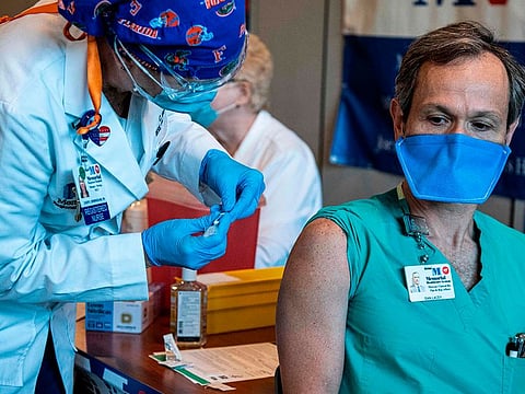Dan Lacey, a medic at Memorial Healthcare System, receives a Pfizer-BioNtech Covid-19 vaccine from Cheryl Birmingham at Memorial Healthcare System, in Miramar, Florida on December 14, 2020. - The United States kicked off a mass vaccination drive Monday hoping to turn the tide on the world's biggest coronavirus outbreak, as the country's death toll neared a staggering 300,000. (Photo by CHANDAN KHANNA / AFP)