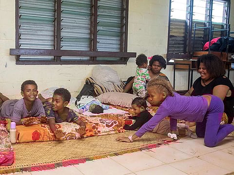A Fijian family takes refuge in a temporary shelter from the strong damaging winds in the capital city of Suva on December 17, 2020