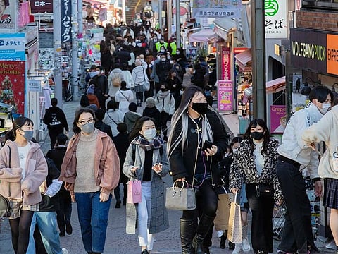 People wearing face masks walk through a famed shopping street in the Harajuku neighbourhood in Tokyo.
