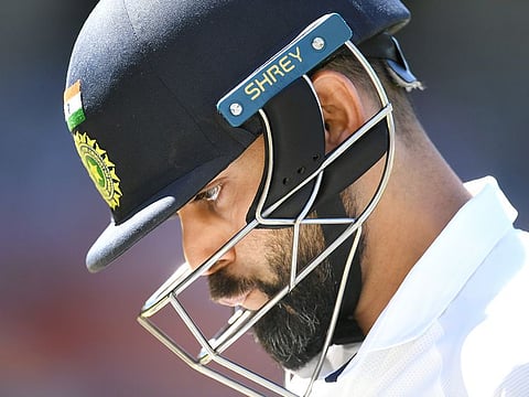Indian captain Virat Kohli leaves the field after his dismissal by Australian bowler Pat Cummins for 4 runs.
