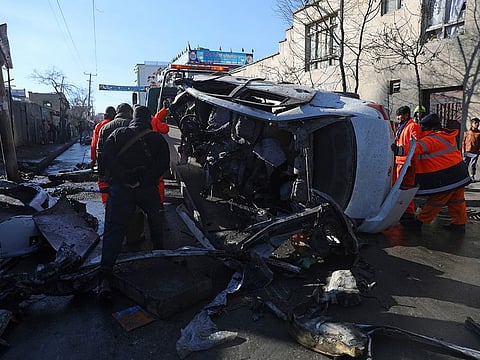 Afghan security personnel and municipality workers remove a damaged vehicle after a roadside bomb attack in Kabul, on Tuesday.