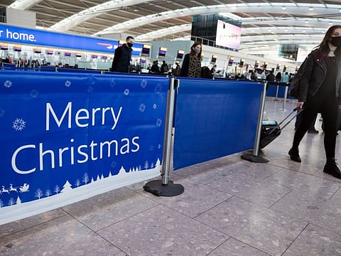 A passenger passes a 'Merry Christmas' sign in the check-in area in at London Heathrow.