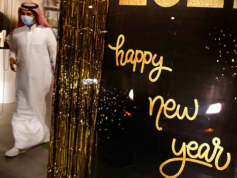 A man wearing a mask to protect from the coronavirus leaves a gift shop decorated for the New Year in Jiddah, Saudi Arabia, Friday, Dec. 25, 2020.