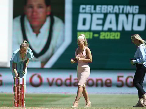 Daughters of former Australian cricketer Dean Jones, Phoebe, left, and Augusta walk with their mother, Jane, right, for a tribute for the late batsman during the tea break on day one of the Boxing Day cricket test between India and Australia at Melbourne Cricket Ground