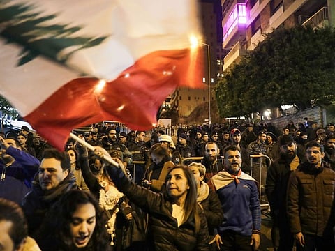 Lebanese protesters wave the national flag as they gather outside the house of Lebanon's new prime minister in the capital Beirut, calling for resignation less than 10 days after he was appointed, on December 28, 2019.