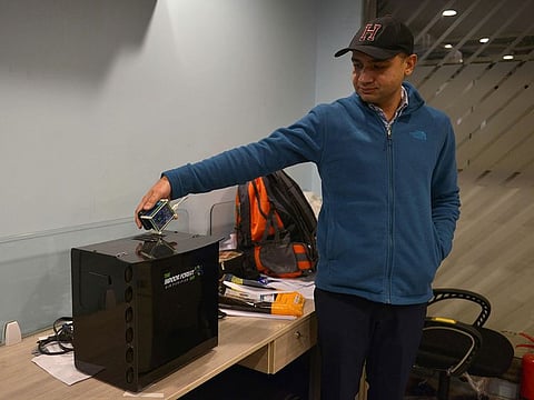 In this picture taken on December 6, 2019, inventor Hasan Zaidi checks the air quality next to his new air purifier device at the office of a customer in Lahore