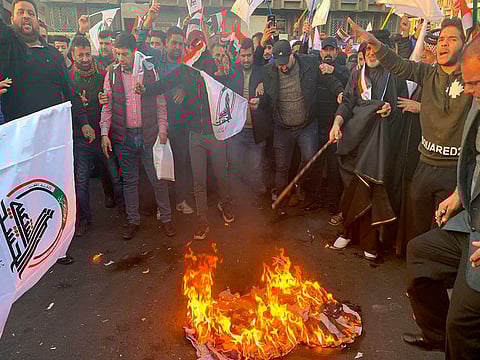 Protesters burn representations of a U.S. flag during a protest against the U.S. strikes on the Hezbollah Brigades militia, in Tahrir Square