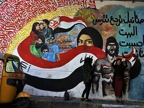 Women stand near a mural in a tunnel during ongoing anti-government protests in downtown Baghdad, Iraq, Sunday, Dec. 29, 2019.