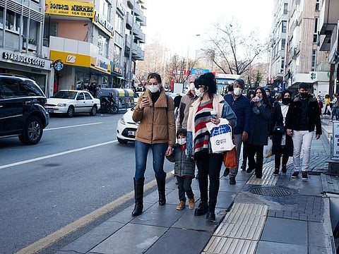 People wearing masks to help protect against the spread of COVID-19, walk along a busy shopping street, in Ankara.