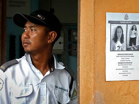 In this Aug. 11, 2019, file photo, a security guard stands next to a notice showing Nora Anne Quoirin, in Seremban, Malaysia. A Malaysian coroner ruled Monday, Jan. 4, 2021 the death of the French-Irish teen, whose body was found near a Malaysian jungle resort where she vanished while on holiday, was most likely a misadventure that didn't involve other people.