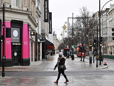 A pedestrian wearing a mask walks past shops closed down due to to lockdown restrictions, on an empty Oxford Street as Britain enters another national lockdown in London on January 5, 2021.