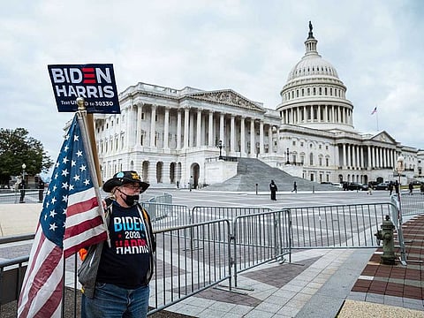 A counter-protester in holding a sign in support of President-elect Joe Biden and vice-president-elect Kamala Harris stands before Capitol Building on January 6, 2021 in Washington, DC.