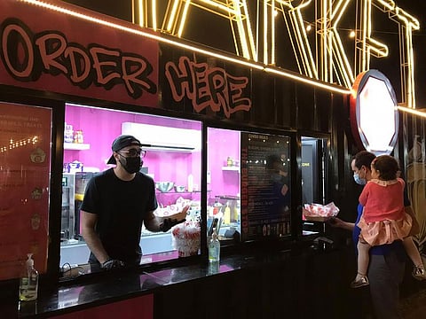Shoayb Ajmal serving a customer at The Burger Joint at the Ripe Market in the Dubai Police Academy Park in Dubai.