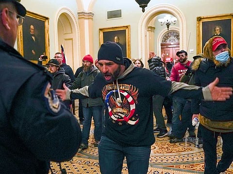 Trump supporters gesture to US Capitol Police in the hallway outside the Senate chamber after breaching the halls of the Capitol in Washington, Wednesday, Jan. 6, 2021.