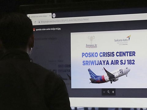 A man stands near an LCD screen installed at a crisis center set up following a report that a Sriwijaya Air passenger jet has lost contact with air traffic controllers after take off, at Soekarno-Hatta International Airport in Tangerang, Indonesia,Saturday, Jan. 9, 2021.
