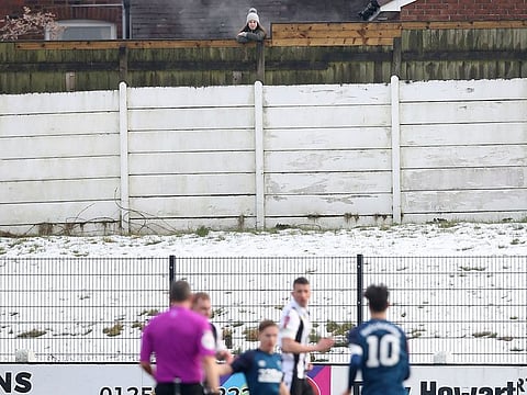 A spectator watches the game from behind a fence, during the English FA Cup third round match between Chorley and Derby County, at Victory Park in Chorley