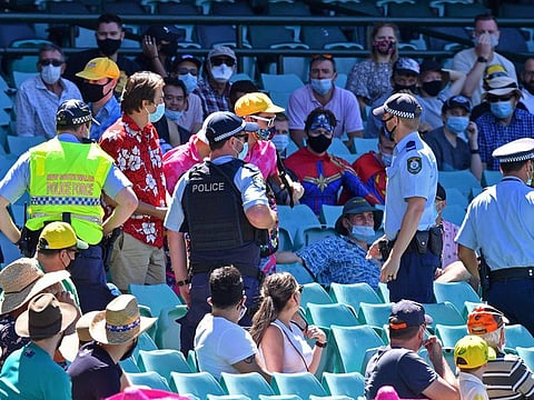 This file photo taken on January 10, 2021 shows police speaking to spectators as the game was halted after allegedly some remarks were made by the spectators on the fourth day of the third cricket Test match between Australia and India at the Sydney Cricket Ground (SCG) in Sydney.