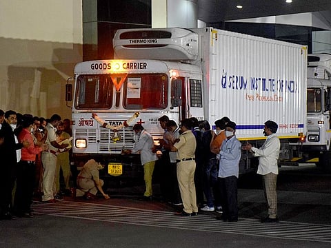 A police officer performs prayers in front of a truck carrying first consignment of Covishield, a coronavirus disease vaccine developed by AstraZeneca and Oxford University, before it leaves from Serum Bio-Pharma Park of Serum Institute of India, for its distribution, in Pune, on January 12, 2021.