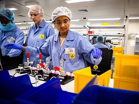 In this picture taken on December 21, 2020, employees work on the production line of a COVID-19 coronavirus home test unit that has been granted an Emergency Use Authorization (EUA) by the US Food and Drug Administration (FDA), at the production facility of Australian digital diagnostics company Ellume in Brisbane. Ellume's product delivers results in just 15 minutes and will soon be available over the counter in pharmacies across the country worst-hit by the pandemic.