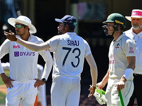 India's Mohammed Siraj (C) gestures next to Australia's captain Tim Paine (2R) as the game was halted after allegedly some remarks were made by the spectators on the fourth day of the third cricket Test match between Australia and India at the Sydney Cricket Ground