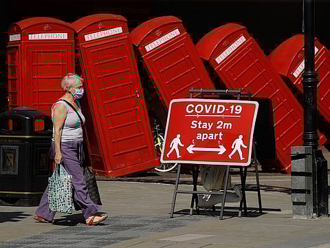 File photo: A sign requesting people stay two metres apart to try to reduce the spread of COVID-19 is displayed in front of "Out of Order" a 1989 red phone box sculpture by British artist David Mach, in London.