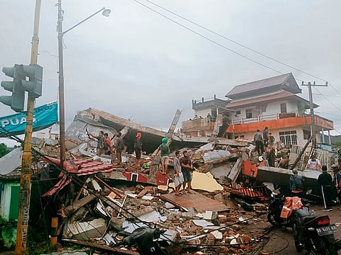 Residents inspect earthquake-damaged buildings in Mamuju, West Sulawesi, Indonesia, Friday, Jan. 15, 2021.