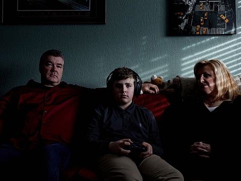 John and Cathleen Reichert watch as their son, James, plays video games