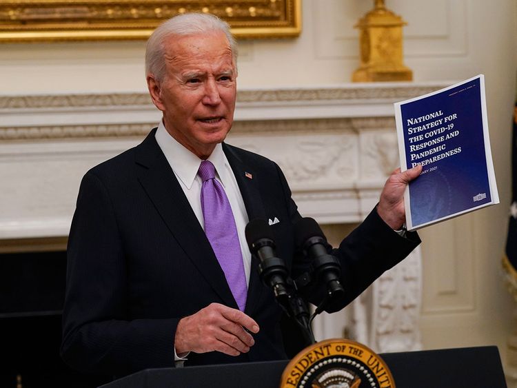 President Joe Biden holds a booklet as he speaks in the White House