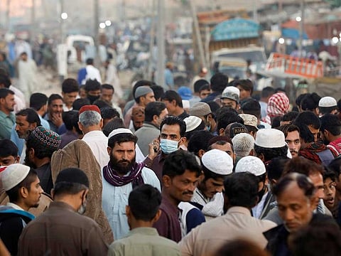 A man wearing a protective mask walks through a crowd of people along a makeshift market as the outbreak of the coronavirus disease (COVID-19) continues, in Karachi, Pakistan January 17, 2021.
