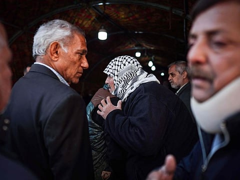 People console Louai Al Nuaimi (centre), father of two Iraqi youngsters, Omar and Ali, killed in Baghdad's twin suicide attacks, during a condolences ceremony in Baghdad's Cairo neighbourhood, on January 22, 2021.