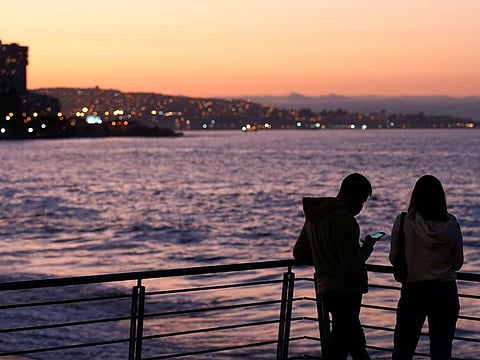 A man checks his cell phone after receiving a message from the national emergency office, ONEMI, urging people to abandon coastal areas after a quake at the Chilean Antarctic territory, in Vina del Mar, Chile, on January 23, 2021.