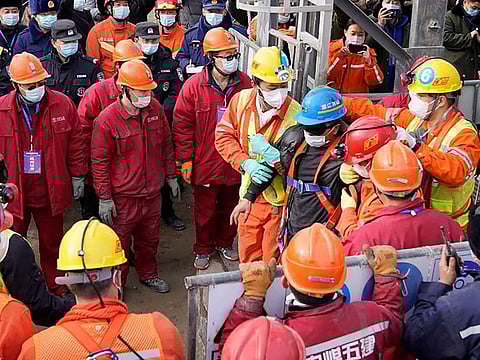 One (C-blue helmet) of 22 Chinese miners is saved from hundreds of metres underground where they had been trapped for two weeks after a gold mine explosion in Qixia, in eastern China's Shandong province on January 24, 2021.