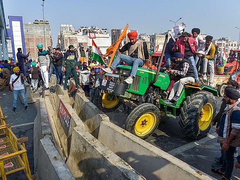 Farmers attempt to break a barricade at Ghazipur border as they participate in 'Kisan Gantantra Parade' in protest against Centre's farm reform laws, on the occasion of 72nd Republic Day, in New Delhi, Tuesday, Jan. 26, 2021.
