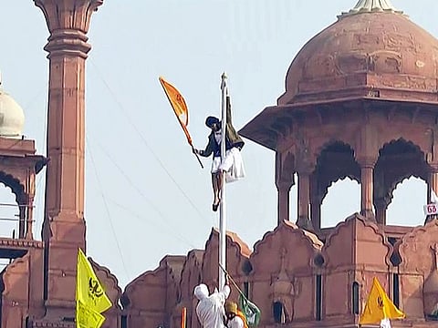 Protesting farmers hoist a flag from the ramparts of the Red Fort on 72nd Republic Day, in New Delhi on Tuesday.