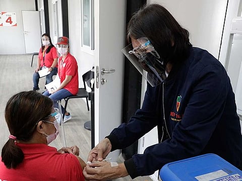 A health worker pretends to inject a volunteer as they still wait for vaccination during a 'COVID-19 Vaccination Dry Run' in Taguig, Philippines.