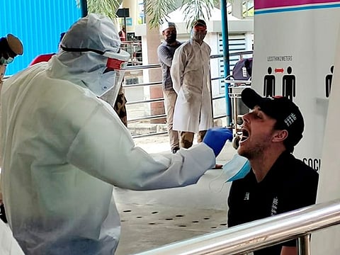 A member of the England team gives his swab sample to a medic for COVID-19 test on arrival at the Chennai airport on Wednesday.