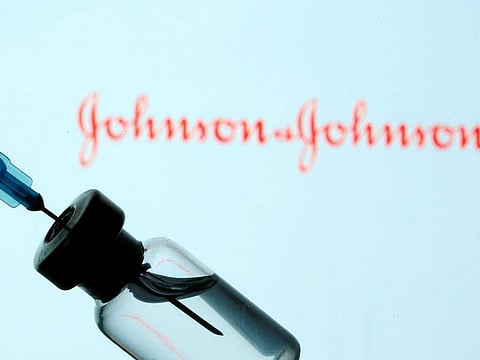 A vial and sryinge are seen in front of a displayed Johnson & Johnson logo in this illustration taken January 11, 2021.