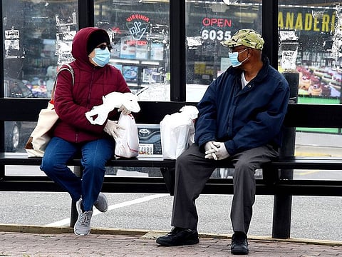 Commuters wearing face masks wait for their bus amid the coronavirus pandemic on in Arlington, Virginia.