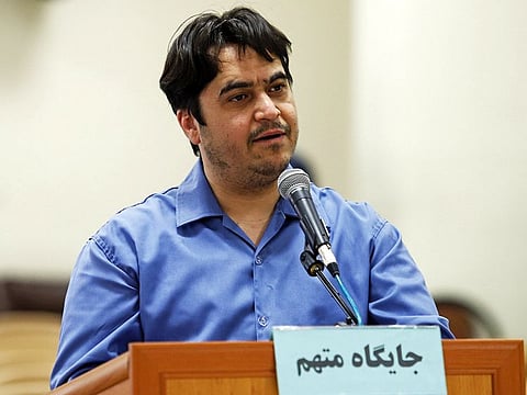 In this June 2, 2020 photo, journalist Ruhollah Zam speaks during his trial at the Revolutionary Court, in Tehran, Iran. Iran. The judiciary spokesman, Gholamhossein Esmaili, announced Tuesday, June 30, 2020 that Zam, a journalist whose online work helped inspire the 2017 economic protests and who returned from exile to Tehran was sentenced to death. The Persian writing on the podium reads, "defendant's place."