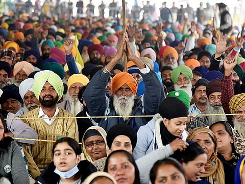 Farmers raise slogans during an ongoing protest against the new farm laws, at the Singhu border in New Delhi on Wednesday.