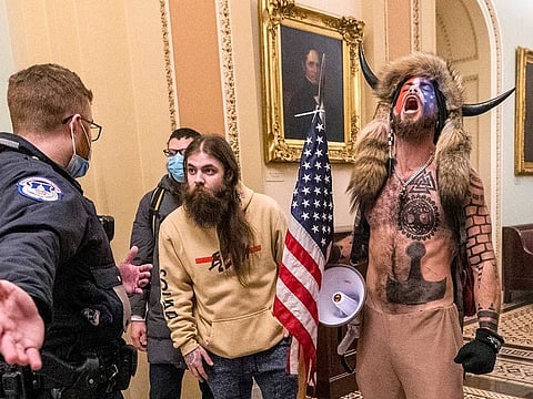 In this Wednesday, Jan. 6, 2021 file photo, supporters of President Donald Trump, including Jacob Chansley, right with fur hat, are confronted by US Capitol Police officers outside the Senate Chamber in the Capitol in Washington