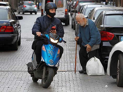 An elderly man uses a stick to walk, during a lockdown to curb the spread of COVID-19, in Beirut.