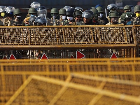 Police stand guard as farmers continue to protest along a highway in Ghazipur on the outskirts of New Delhi on Saturday. Tens of thousands of protesting Indian farmers have blocked highways across the country in defiance of the government’s internet and phone blackout, facing off against a heavy security deployment stationed behind rows of razor wire and concrete blocks.