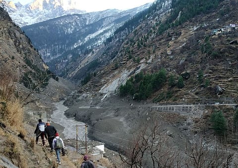 People walk past a destroyed dam after a Himalayan glacier broke and crashed into the dam at Raini Chak Lata village in Chamoli district, northern state of Uttarakhand, India, February 7, 2021.