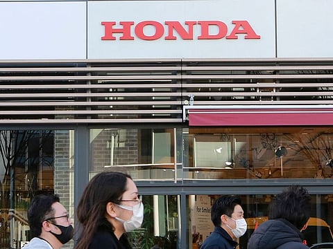People pass by a Honda showroom in Tokyo on February 9. Honda cut its sales target by 100,000 vehicles, or 2.2 per cent, on Tuesday to 4.5 million cars, while Nissan lowered its target by 150,000 vehicles, or 3.6 per cent, to 4.015 million units as a chips shortage forced both companies to curb output.