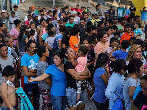 In this Aug. 30, 2019, file photo, migrants, many of whom were returned to Mexico under the Trump administration's "Remain in Mexico" policy, wait in line to get a meal in an encampment near the Gateway International Bridge in Matamoros, Mexico.