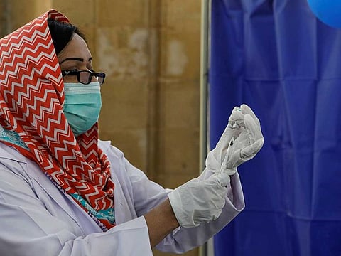 A paramedic prepares a vaccine to administer to a worker at a vaccination centre in Karachi.